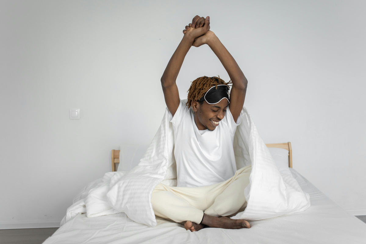 Man waking up and stretching in bed representing morning hydration